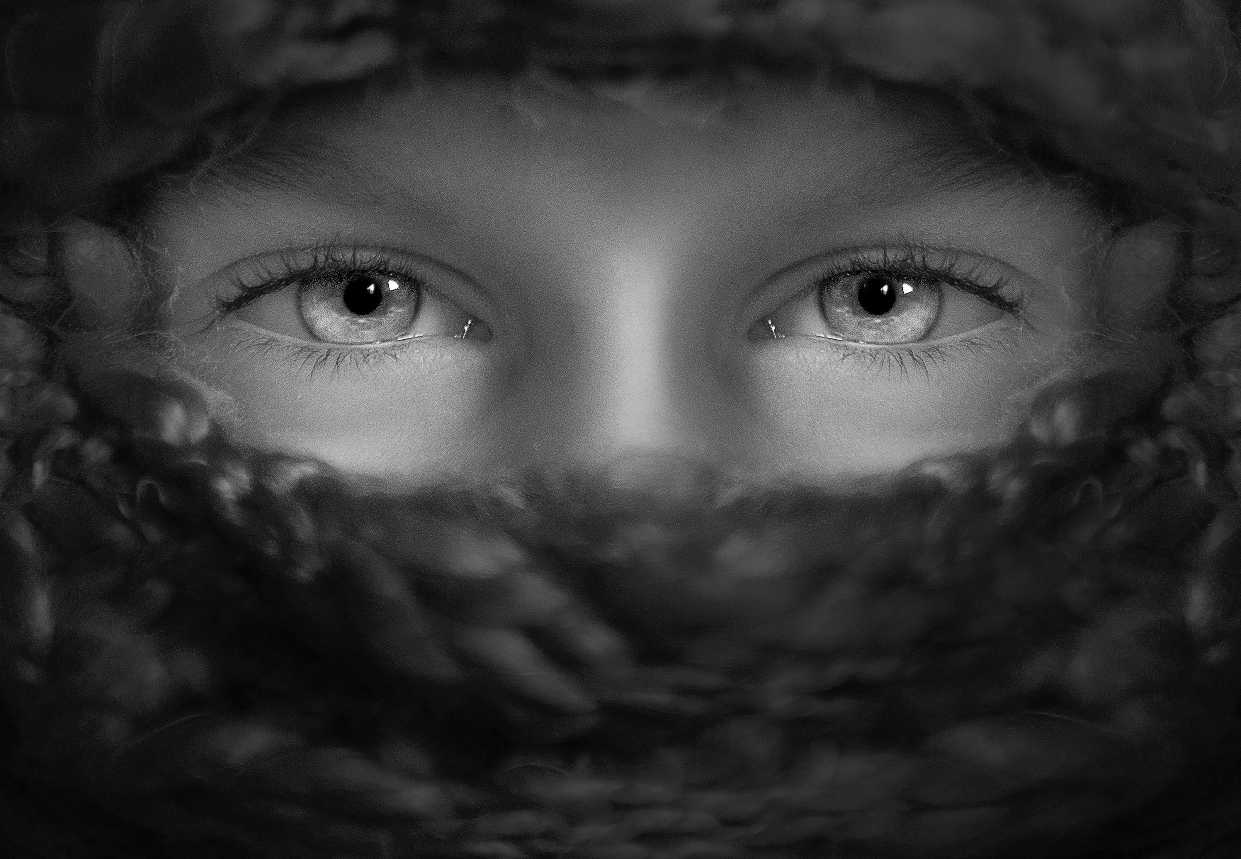 grå bild med person som har täckt ansikte och endast ögonen syns